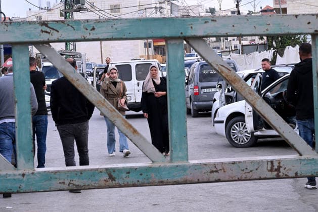 Palestinians walk behind an Israeli erected locked gate that blocks cars from moving to and from the village of Sair, near Hebron in the West Bank, on Tuesday, September 29, 2026. Israel declared a West Bank military closure to restrict Palestinian movement during the Jewish holiday of Sukkot from September 27 - October 3, 2026.  JER2026092912 DEBBIExHILL