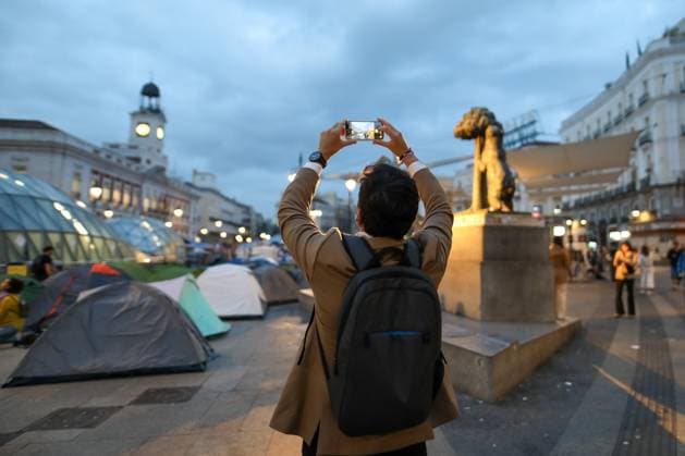 September 29, 2026, Madrid, Spain: A man takes a photo with his mobile phone at Madrid s Puerta del Sol..Fourth day of the encampment at Madrid s Puerta del Sol. Hundreds of tents remain set up by housing activists who organized the occupation of the square in response to the eviction of MaricarmenÃ¢â‚¬a woman in her eightiesÃ¢â‚¬from her home by a vulture fund. Madrid Spain - ZUMAs197 20260929_aaa_s197_300 Copyright: xDavidxCanalesx