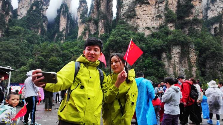ZHANGJIAJIE, CHINA - OCTOBER 01: Tourists gather to celebrate the 77th anniversary of the founding of the People s Republic of China with colorful activities including welcome drums, door-blocking wine, hand-waving dances, cake tasting and folk singing at Bailong Elevator viewing platform in Zhangjiajie National Forest Park on October 1, 2026 in Zhangjiajie, Hunan Province of China.  Copyright: xVCGx 111670911310