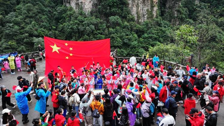 ZHANGJIAJIE, CHINA - OCTOBER 01: Tourists gather to celebrate the 77th anniversary of the founding of the People s Republic of China amid colorful activities including welcome drums, blocking-door wine, hand-waving dances, cake tasting and mountain songs at Bailong Elevator viewing platform in Zhangjiajie National Forest Park on October 1, 2026 in Zhangjiajie, Hunan Province of China. The park organized various events to attract domestic and international visitors during the National Day holiday.  Copyright: xVCGx 111670911301