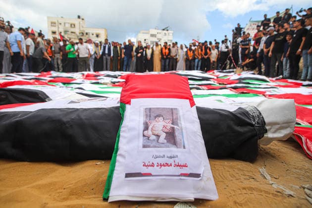 Gaza Mass Funeral For Victim A Palestinian flag-draped shroud bearing a printed photograph and identification label lies in the foreground as mourners stand around rows of other shrouds in Gaza City, Gaza Strip, on October 1, 2026. Gaza Civil Defense said the funeral was held for the remains of 105 people recovered from beneath the rubble of the Al-Taj residential complex and surrounding buildings in the Al-Yarmouk area, which were destroyed in Israeli strikes on October 25, 2023. The remains were taken for burial at Sheikh Radwan cemetery. Gaza Gaza Strip Palestinian Territories Copyright: xRamezxHabboubx