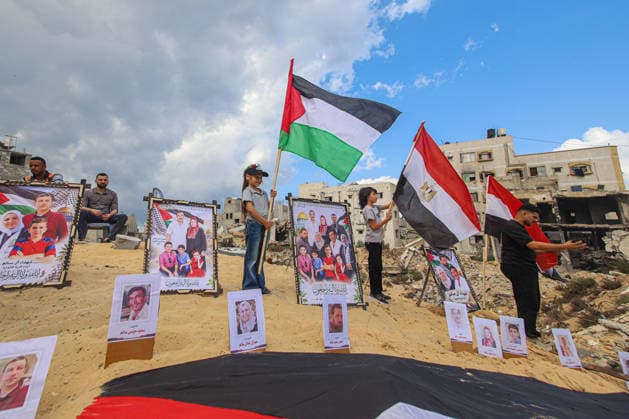 Gaza Mass Funeral For Victim Palestinian and Egyptian flags rise above a display of portraits and memorial posters arranged on rubble during a mass funeral in Gaza City, Gaza Strip, on October 1, 2026. Gaza Civil Defense said the funeral was held for the remains of 105 people recovered from beneath the rubble of the Al-Taj residential complex and surrounding buildings in the Al-Yarmouk area, which were destroyed in Israeli strikes on October 25, 2023. The remains were taken for burial at Sheikh Radwan cemetery. Gaza Gaza Strip Palestinian Territories Copyright: xRamezxHabboubx