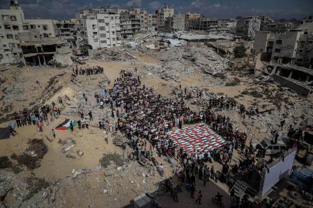 Gaza Funeral For Recovered Victims An aerial view shows a large crowd gathered around rows of Palestinian flag-draped shrouds in a heavily damaged area of Gaza City, Gaza Strip, on October 1, 2026. Gaza Civil Defense said the remains were among those of 105 Palestinians recovered during a 17-day search of the Al-Taj residential block in the Al-Yarmouk area, which was struck by Israel on October 25, 2023. Gaza City Gaza Strip Palestinian Territories Copyright: xMohammedxMxSkaikx