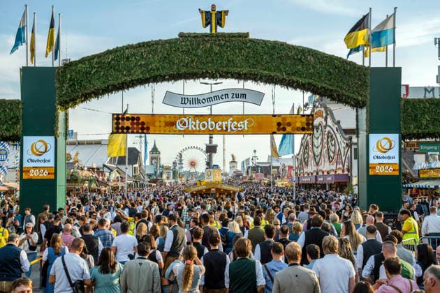 Willkommen zum Oktoberfest, hunderte Wiesnbesucher strömen durch den Haupteingang auf die Festwiese, München, 1. Oktober 2026 Deutschland, München, 1. Oktober 2026, Oktoberfest 2026, Willkommen zum Oktoberfest, Haupteingang der Wiesn, Wiesnbesucher strömen unter dem begrünten Torbogen auf die Festwiese, davor kontrolliert eine Kette von Sicherheitskräften die Besucher, Donnerstagnachmittag um 17:15 Uhr, bayerisch, Volksfest, Bayern,