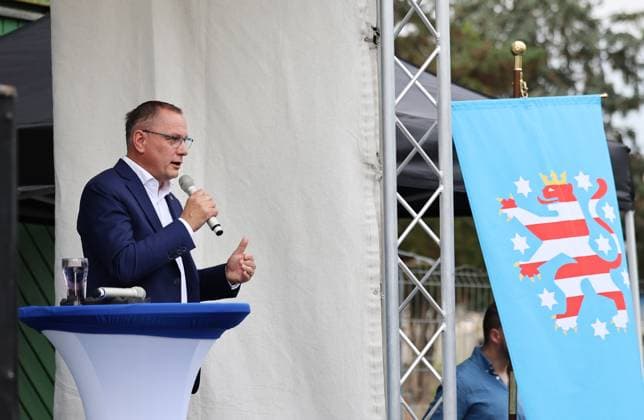 Auf eine Bratwurst mit Haseloff und Chrupalla 01.10.2026, Doellstaedt, Veranstaltung der AfD bei Kiesling Bedachungen, Auf eine Bratwurst mit Landtagsabgeordneten Daniel Haseloff (AfD) und AfD Bundessprecher Tino Chrupalla im Bild: Tino Chrupalla haelt eine Rede auf der Buehne, rechts haengt eine Flagge mit dem Thueringer Loewen
