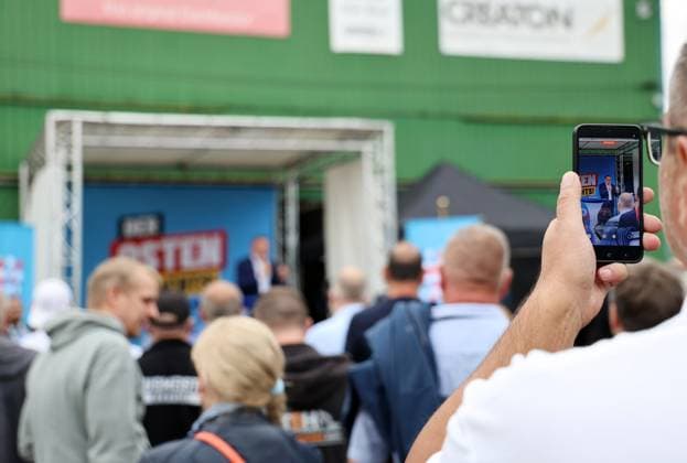 Auf eine Bratwurst mit Haseloff und Chrupalla 01.10.2026, Doellstaedt, Veranstaltung der AfD bei Kiesling Bedachungen, Auf eine Bratwurst mit Landtagsabgeordneten Daniel Haseloff (AfD) und AfD Bundessprecher Tino Chrupalla im Bild: Tino Chrupalla haelt eine Rede auf der Buehne, im Hintergrund steht der Satz Der Osten machts, ein Besucher filmt die Rede mit einem Smartphone