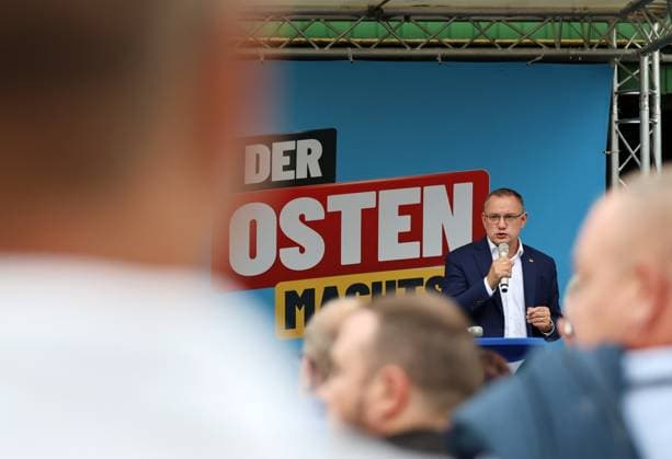 Auf eine Bratwurst mit Haseloff und Chrupalla 01.10.2026, Doellstaedt, Veranstaltung der AfD bei Kiesling Bedachungen, Auf eine Bratwurst mit Landtagsabgeordneten Daniel Haseloff (AfD) und AfD Bundessprecher Tino Chrupalla im Bild: Tino Chrupalla haelt eine Rede auf der Buehne, im Hintergrund steht der Satz Der Osten machts