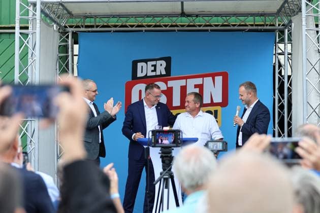 Auf eine Bratwurst mit Haseloff und Chrupalla 01.10.2026, Doellstaedt, Veranstaltung der AfD bei Kiesling Bedachungen, Auf eine Bratwurst mit Landtagsabgeordneten Daniel Haseloff (AfD) und AfD Bundessprecher Tino Chrupalla im Bild: Tino Chrupalla mit dem Inhaber von Kiesling Bedachungen Mark Kiesling und Daniel Haseloff (AfD) auf der Buehne, im Hintergrund steht der Satz Der Osten machts, viele Fotos werden gemacht