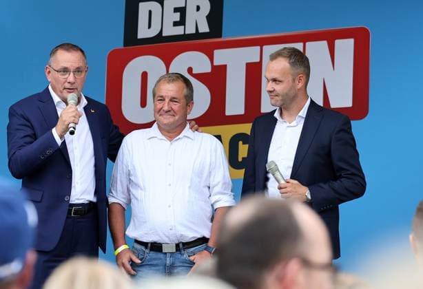 Auf eine Bratwurst mit Haseloff und Chrupalla 01.10.2026, Doellstaedt, Veranstaltung der AfD bei Kiesling Bedachungen, Auf eine Bratwurst mit Landtagsabgeordneten Daniel Haseloff (AfD) und AfD Bundessprecher Tino Chrupalla im Bild: Tino Chrupalla mit dem Inhaber von Kiesling Bedachungen Mark Kiesling und Daniel Haseloff (AfD) auf der Buehne, im Hintergrund steht der Satz Der Osten machts