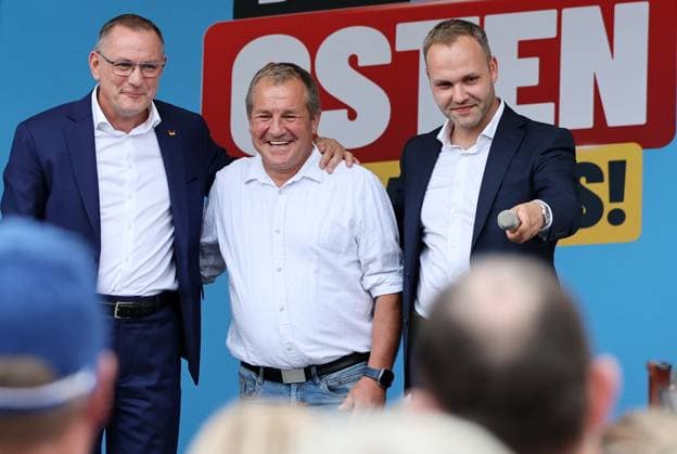 Auf eine Bratwurst mit Haseloff und Chrupalla 01.10.2026, Doellstaedt, Veranstaltung der AfD bei Kiesling Bedachungen, Auf eine Bratwurst mit Landtagsabgeordneten Daniel Haseloff (AfD) und AfD Bundessprecher Tino Chrupalla im Bild: Tino Chrupalla mit dem Inhaber von Kiesling Bedachungen Mark Kiesling und Daniel Haseloff (AfD) auf der Buehne, im Hintergrund steht der Satz Der Osten machts