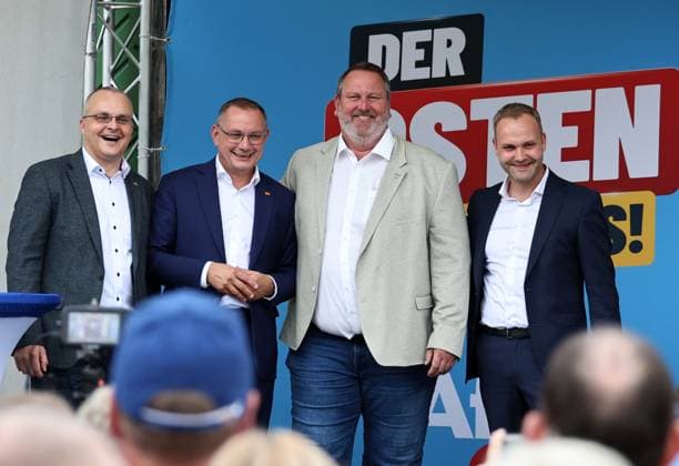 Auf eine Bratwurst mit Haseloff und Chrupalla 01.10.2026, Doellstaedt, Veranstaltung der AfD bei Kiesling Bedachungen, Auf eine Bratwurst mit Landtagsabgeordneten Daniel Haseloff (AfD) und AfD Bundessprecher Tino Chrupalla im Bild: Marcus Buehl (MdB, AfD Bruder von Andreas Buehl (CDU)), Tino Chrupalla (Bundessprecher AfD), Stephan Steinbrueck (AfD) und Daniel Haseloff (AfD) auf der Buehne fuer ein gemeinsames Foto, im Hintergrund steht der Satz Der Osten machts