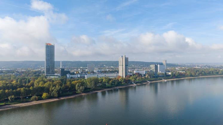 Extremes Niedrigwasser legt Rheinufer in Bonn frei Bonn, 02.10.2026: Drohnenaufnahme des Rheins in Bonn-Gronau. Das stark zurückgegangene Wasser legt auf der linken Rheinseite einen großflächigen, ausgetrockneten Uferbereich frei. Auf der rechten Bildseite ist im Hintergrund der Post Tower sowie weitere Gebäude des Bonner Regierungsviertels zu sehen. In der Ferne zeichnet sich der Venusberg ab. Der Rhein führt derzeit außergewöhnlich wenig Wasser. Am Pegel Bonn wurden am 2. Oktober 2026 gegen 00:30 Uhr 61 Zentimeter gemessen. Bonn Ramersdorf Nordrhein-Westfalen Deutschland