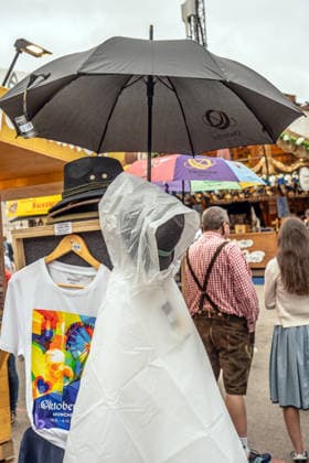 Wiesn bis zum Schluss im Wetterglück: Regenschirme und Regenponchos bleiben auch am Freitag Ladenhüter unter den Wiesn-Souvenirs, München, 2. Oktober 2026 Deutschland, München, 2. Oktober 2026, Wiesn bis zum Schluss im Wetterglück: Regenschirme und Regenponchos bleiben auch am Freitag Ladenhüter unter den Wiesn-Souvenirs, trotz schwerer Regenwolken über dem Festgelände fiel am Freitagmittag kein einziger Tropfen, Souvenirs an der offiziellen Oktoberfest-Info am Wiesneingang, Bayern