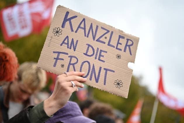 News Bilder des Tages Eine Teilnehmerin haelt am 02.10.2026 einen Pappkarton mit dem Satz Kanzler an die Front waehrend einer Kundgebung vor dem Brandenburger Tor unter dem Motto Unzwingbar - Kein Bock auf Krieg und Wehrpflicht . Zu den Veranstaltern der Demonstration zaehlen unter anderem Attac, die Deutsche Friedensgesellschaft und der Internationale Jugendverband. In einem vorab verbreiteten Aufruf stellten sich die Organisationen etwa gegen eine Wiedereinfuehrung der Wehrpflicht und die Anwerbung Jugendlicher unter 18 Jahren fuer die Bundeswehr. Das Buendnis forderte zudem mehr Geld fuer Bildung, Gesundheit und Soziales statt fuer Krieg. Angekuendigt waren Redebeitraege unter anderem von Gewerkschaftern, Schueler- und Studentengruppen und der Schulstreikb Copyright: epd-bild ChristianxDitsch 18