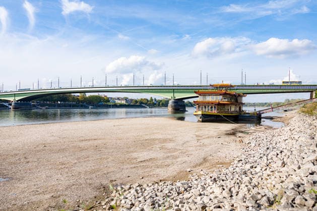 Niedrigwasser am Rhein in Bonn: Das China-Schiff an der Kennedybrücke - 02.10.26 Blick auf die Kennedybrücke in Bonn: Durch die anhaltende Niedrigwasserlage liegt das sogenannte China-Schiff, das seit 2023 geschlossene Restaurantschiff Ocean Paradise , fast trocken. Die Schifffahrt ist eingeschränkt, der Pegel Bonn liegt bei 64 cm und damit nur wenig über dem Rekordtief von 58 cm vom 29. September. Bonn Beuel Nordrhein-Westfalen Deutschland Copyright: xMarcxJohnx