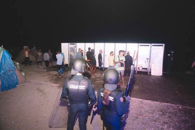 October 3, 2026, Ceuta, Ceuta, Spain: Riot police officers stand in front of the portable toilets of a makeshift migrant camp in Ceuta at night. Riot police escorted firefighters through the camp on the night of October 3 to put out the fires that people living there use to cook their food. Thousands of migrants, most of them young Moroccan men, have been living in makeshift settlements in the Spanish North African enclave of Ceuta since a mass arrival at the end of July 2026 set off a migration and political crisis. Ceuta Spain - ZUMAs392 20261003_zip_s392_005 Copyright: xFabianxSuspensivox