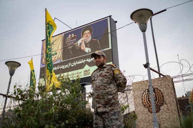 Opening Ceremony Of Second City-Square Military Training Camp An Iranian Army serviceman in uniform stands beneath a portrait of Hassan Nasrallah, the late secretary general of Lebanon s Hezbollah, during the opening ceremony of the second city-square military training camp for self-sacrificing forces in downtown Tehran, Iran, on October 3, 2026. The camp was established by the Basij paramilitary force, with personnel from the Islamic Republic of Iran Army responsible for training the volunteers. Tehran Tehran Iran  Copyright: xMortezaxNikoubazlx originalFilename: nikoubazl-openingc261003_npn3f.jpg