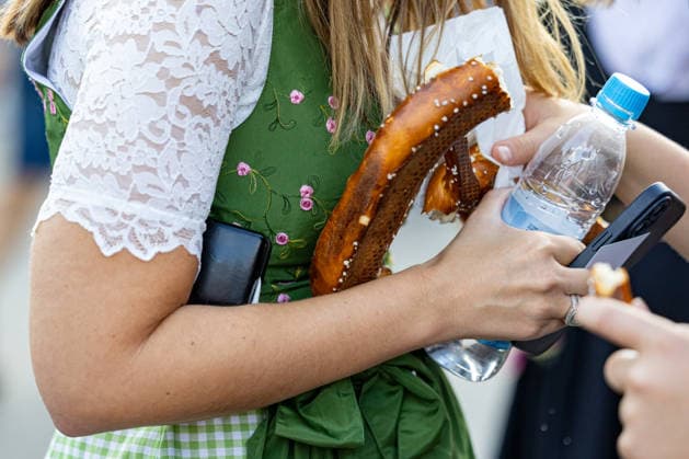 Oktoberfest 2026 in München 04.10.2026: Eine Besucherin im Dirndl hält eine Brezn und eine Flasche Wasser auf dem Festgelände. Das 191. Oktoberfest fand 2026 vom 19. September bis 4. Oktober auf der Theresienwiese statt. Das Münchner Oktoberfest zählt zu den größten Volksfesten der Welt und zieht jährlich Millionen Besucher aus Deutschland und dem Ausland an. Muenchen Theresienwiese Bayern Deutschland