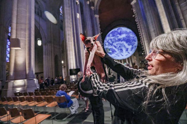 October 4, 2026, New York, New York, United States: A woman holds her cat with the Gaia in the background. The monumental illuminated Earth installation by British artist LUKE JERRAM, during the annual St. Francis Day Blessing of the Earth and Animals at the Cathedral of St. John the Divine in New York. The celebration also marked the 800th anniversary of the death of St. Francis of Assisi. New York United States  - ZUMAo116 20261004_znp_o116_054 Copyright: xBiancaxOterox