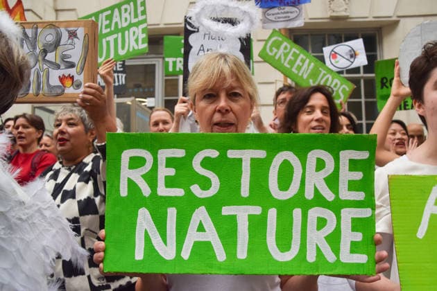 October 6, 2026, London, England, United Kingdom: An activist holds a Restore Nature placard during a protest by the climate action group Fossil Free London against the Rosebank oil field and the Jackdaw gas field outside the Department for Energy Security and Net Zero. London United Kingdom  - ZUMAv130 20261006_zip_v130_007 Copyright: xVukxValcicx