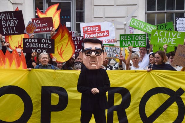 October 6, 2026, London, England, United Kingdom: Activists from the climate action group Fossil Free London stage a protest against the Rosebank oil field and the Jackdaw gas field outside the Department for Energy Security and Net Zero. Activists dressed as angels urge a protester wearing an Andy Burnham mask to stop the fossil fuel projects in the North Sea while activists dressed as demons urge him to drill for more oil. London United Kingdom  - ZUMAv130 20261006_zip_v130_032 Copyright: xVukxValcicx