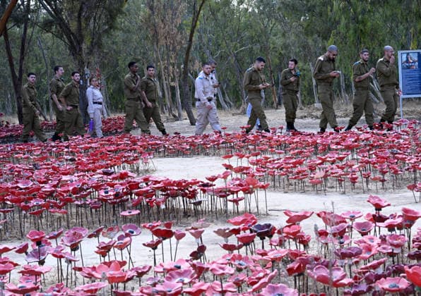 Israeli soldiers walk past an installation of red poppies in remembrance to the hundreds of victims killed by Hamas on October 7, 2023, at the Nova Festival Memorial site in Re im, near the Gaza border on Monday, October 6, 2026. Israel is marking three years since the Hamas attack that killed 1,200 people and 251 were taken hostage into Gaza.  JER2026100614 DEBBIExHILL
