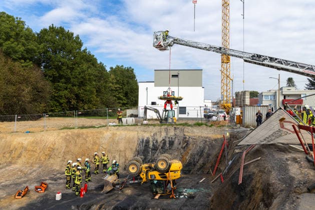 RECORD DATE NOT STATED Feuerwehr und Rettungsdienst versorgen eine Person neben einem umgestürzten Radlader in einer Baugrube an der Charlottenstraße in Bochum-Wiemelhausen. Die Baumaschine war etwa dreieinhalb bis vier Meter tief abgestürzt und auf dem Dach liegen geblieben. Einsatzkräfte sichern das Fahrzeug mit Stützen.