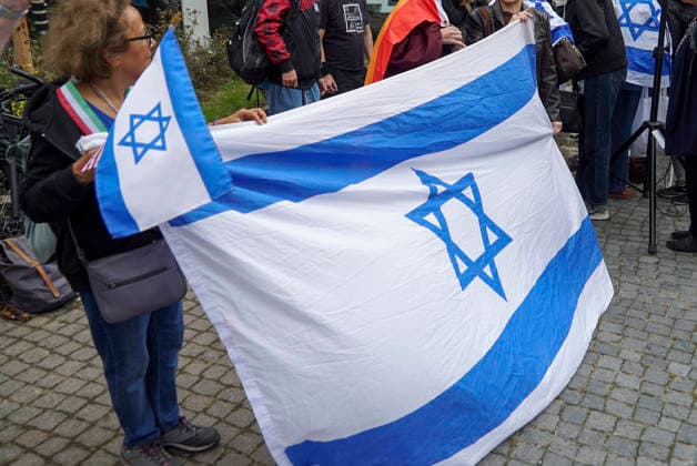 CNTV MAHNWACHE - Demonstranten auf der Strasse die Teilnehmer mit Deutschland Israel Fahnen bei der Mahnwache anlaesslich des 3.Jahrestages des Ueberfalls und Massakers in Israel Menschen versammeln sich die Menschen vor dem Audimax im Grindelvietel in Hamburg am 07.10.2026 Hamburg Deutschland