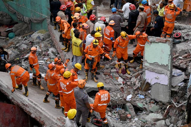 NEW DELHI, INDIA - OCTOBER 7: National Disaster Response Force (NDRF) jawans, Delhi Fire Service personnel, and local residents navigate heavy rubble during a search and rescue operation after a four-storey residential building collapsed in the New Seemapuri area of Shahdara on October 7, 2026, in New Delhi, India. The structural collapse occurred around 3:30 PM behind the local fish market, trapping multiple residents under concrete slabs and damaging two adjoining houses. At least one minor died while eight people were rescued and rushed to Rajiv Gandhi Super Speciality Hospital for emergency medical treatment as sniffer dogs and excavators worked late into the evening to locate remaining trapped survivors. (Photo by Ishant Chauhan Hindus