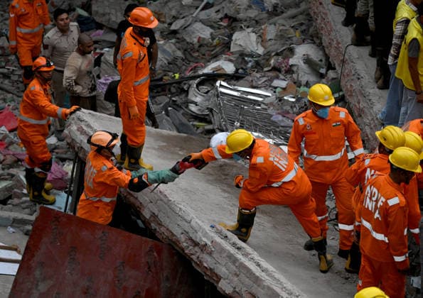 NEW DELHI, INDIA - OCTOBER 7: National Disaster Response Force (NDRF) jawans, Delhi Fire Service personnel, and local residents navigate heavy rubble during a search and rescue operation after a four-storey residential building collapsed in the New Seemapuri area of Shahdara on October 7, 2026, in New Delhi, India. The structural collapse occurred around 3:30 PM behind the local fish market, trapping multiple residents under concrete slabs and damaging two adjoining houses. At least one minor died while eight people were rescued and rushed to Rajiv Gandhi Super Speciality Hospital for emergency medical treatment as sniffer dogs and excavators worked late into the evening to locate remaining trapped survivors. (Photo by Ishant Chauhan Hindus