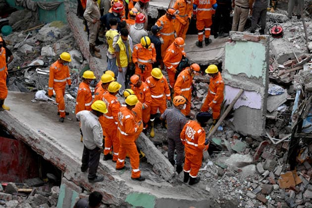 NEW DELHI, INDIA - OCTOBER 7: National Disaster Response Force (NDRF) jawans, Delhi Fire Service personnel, and local residents navigate heavy rubble during a search and rescue operation after a four-storey residential building collapsed in the New Seemapuri area of Shahdara on October 7, 2026, in New Delhi, India. The structural collapse occurred around 3:30 PM behind the local fish market, trapping multiple residents under concrete slabs and damaging two adjoining houses. At least one minor died while eight people were rescued and rushed to Rajiv Gandhi Super Speciality Hospital for emergency medical treatment as sniffer dogs and excavators worked late into the evening to locate remaining trapped survivors. (Photo by Ishant Chauhan Hindus