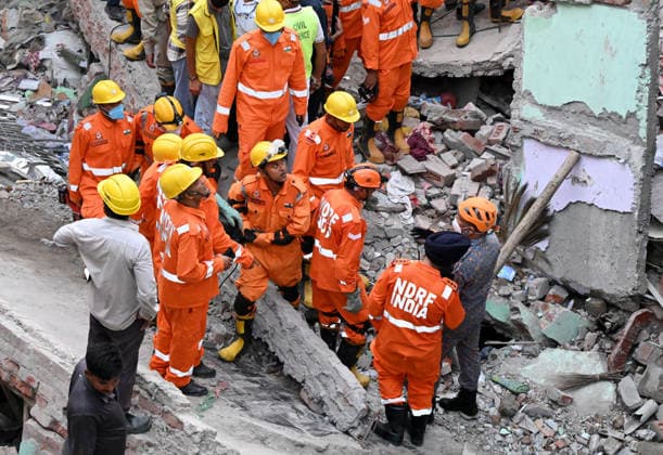 NEW DELHI, INDIA - OCTOBER 7: National Disaster Response Force (NDRF) jawans, Delhi Fire Service personnel, and local residents navigate heavy rubble during a search and rescue operation after a four-storey residential building collapsed in the New Seemapuri area of Shahdara on October 7, 2026, in New Delhi, India. The structural collapse occurred around 3:30 PM behind the local fish market, trapping multiple residents under concrete slabs and damaging two adjoining houses. At least one minor died while eight people were rescued and rushed to Rajiv Gandhi Super Speciality Hospital for emergency medical treatment as sniffer dogs and excavators worked late into the evening to locate remaining trapped survivors. (Photo by Ishant Chauhan Hindus