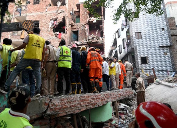NEW DELHI, INDIA - OCTOBER 7: National Disaster Response Force (NDRF) jawans, Delhi Fire Service personnel, and local residents navigate heavy rubble during a search and rescue operation after a four-storey residential building collapsed in the New Seemapuri area of Shahdara on October 7, 2026, in New Delhi, India. The structural collapse occurred around 3:30 PM behind the local fish market, trapping multiple residents under concrete slabs and damaging two adjoining houses. At least one minor died while eight people were rescued and rushed to Rajiv Gandhi Super Speciality Hospital for emergency medical treatment as sniffer dogs and excavators worked late into the evening to locate remaining trapped survivors. (Photo by Ishant Chauhan Hindus