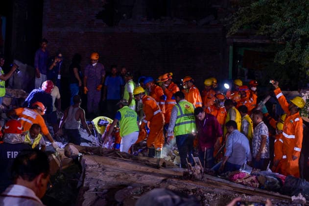 NEW DELHI, INDIA - OCTOBER 7: National Disaster Response Force (NDRF) jawans, Delhi Fire Service personnel, and local residents navigate heavy rubble during a search and rescue operation after a four-storey residential building collapsed in the New Seemapuri area of Shahdara on October 7, 2026, in New Delhi, India. The structural collapse occurred around 3:30 PM behind the local fish market, trapping multiple residents under concrete slabs and damaging two adjoining houses. At least one minor died while eight people were rescued and rushed to Rajiv Gandhi Super Speciality Hospital for emergency medical treatment as sniffer dogs and excavators worked late into the evening to locate remaining trapped survivors. (Photo by Raj K Raj Hindustan T