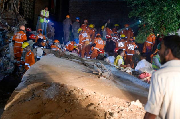 NEW DELHI, INDIA - OCTOBER 7: National Disaster Response Force (NDRF) jawans, Delhi Fire Service personnel, and local residents navigate heavy rubble during a search and rescue operation after a four-storey residential building collapsed in the New Seemapuri area of Shahdara on October 7, 2026, in New Delhi, India. The structural collapse occurred around 3:30 PM behind the local fish market, trapping multiple residents under concrete slabs and damaging two adjoining houses. At least one minor died while eight people were rescued and rushed to Rajiv Gandhi Super Speciality Hospital for emergency medical treatment as sniffer dogs and excavators worked late into the evening to locate remaining trapped survivors. (Photo by Raj K Raj Hindustan T
