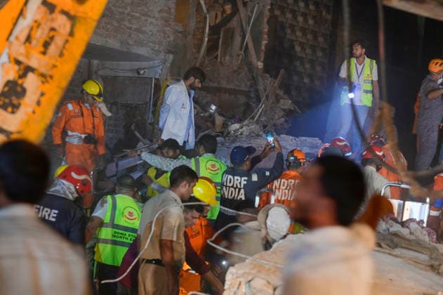 NEW DELHI, INDIA - OCTOBER 7: National Disaster Response Force (NDRF) jawans, Delhi Fire Service personnel, and local residents navigate heavy rubble during a search and rescue operation after a four-storey residential building collapsed in the New Seemapuri area of Shahdara on October 7, 2026, in New Delhi, India. The structural collapse occurred around 3:30 PM behind the local fish market, trapping multiple residents under concrete slabs and damaging two adjoining houses. At least one minor died while eight people were rescued and rushed to Rajiv Gandhi Super Speciality Hospital for emergency medical treatment as sniffer dogs and excavators worked late into the evening to locate remaining trapped survivors. (Photo by Raj K Raj Hindustan T