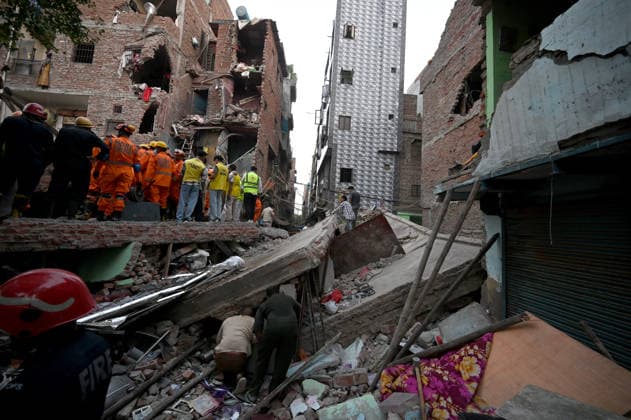 NEW DELHI, INDIA - OCTOBER 7: National Disaster Response Force (NDRF) jawans, Delhi Fire Service personnel, and local residents navigate heavy rubble during a search and rescue operation after a four-storey residential building collapsed in the New Seemapuri area of Shahdara on October 7, 2026, in New Delhi, India. The structural collapse occurred around 3:30 PM behind the local fish market, trapping multiple residents under concrete slabs and damaging two adjoining houses. At least one minor died while eight people were rescued and rushed to Rajiv Gandhi Super Speciality Hospital for emergency medical treatment as sniffer dogs and excavators worked late into the evening to locate remaining trapped survivors. (Photo by Ishant Chauhan Hindus