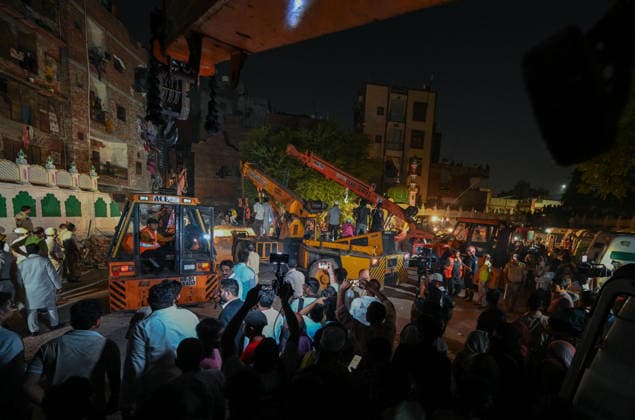 NEW DELHI, INDIA - OCTOBER 7: National Disaster Response Force (NDRF) jawans, Delhi Fire Service personnel, and local residents navigate heavy rubble during a search and rescue operation after a four-storey residential building collapsed in the New Seemapuri area of Shahdara on October 7, 2026, in New Delhi, India. The structural collapse occurred around 3:30 PM behind the local fish market, trapping multiple residents under concrete slabs and damaging two adjoining houses. At least one minor died while eight people were rescued and rushed to Rajiv Gandhi Super Speciality Hospital for emergency medical treatment as sniffer dogs and excavators worked late into the evening to locate remaining trapped survivors. (Photo by Raj K Raj Hindustan T