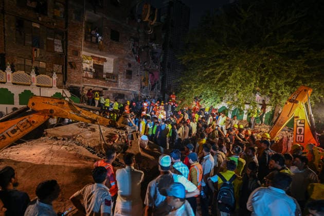 NEW DELHI, INDIA - OCTOBER 7: National Disaster Response Force (NDRF) jawans, Delhi Fire Service personnel, and local residents navigate heavy rubble during a search and rescue operation after a four-storey residential building collapsed in the New Seemapuri area of Shahdara on October 7, 2026, in New Delhi, India. The structural collapse occurred around 3:30 PM behind the local fish market, trapping multiple residents under concrete slabs and damaging two adjoining houses. At least one minor died while eight people were rescued and rushed to Rajiv Gandhi Super Speciality Hospital for emergency medical treatment as sniffer dogs and excavators worked late into the evening to locate remaining trapped survivors. (Photo by Raj K Raj Hindustan T