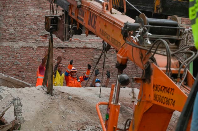 NEW DELHI, INDIA - OCTOBER 7: National Disaster Response Force (NDRF) jawans, Delhi Fire Service personnel, and local residents navigate heavy rubble during a search and rescue operation after a four-storey residential building collapsed in the New Seemapuri area of Shahdara on October 7, 2026, in New Delhi, India. The structural collapse occurred around 3:30 PM behind the local fish market, trapping multiple residents under concrete slabs and damaging two adjoining houses. At least one minor died while eight people were rescued and rushed to Rajiv Gandhi Super Speciality Hospital for emergency medical treatment as sniffer dogs and excavators worked late into the evening to locate remaining trapped survivors. (Photo by Raj K Raj Hindustan T