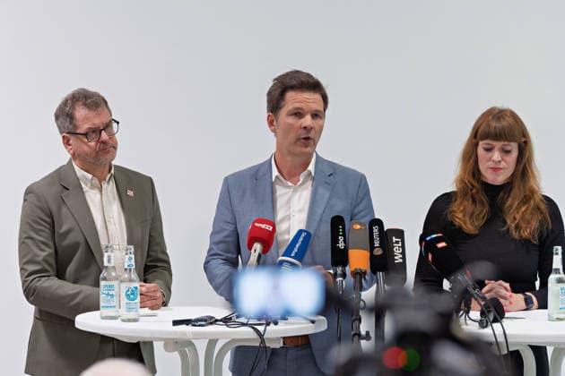 Berlin, 08.10.2026: Steffen Krach (SPD, M.) spricht neben Werner Graf (Bündnis 90 Die Grünen, l.) und Kerstin Wolter-Ehling (Die Linke, r.) beim gemeinsamen Pressestatement nach Abschluss der Vorgespräche ihrer Parteien im Foyer des Hauses der Statistik in die Mikrofone der Medien. Pressestatement von Linke, Grünen und SPD in Berlin