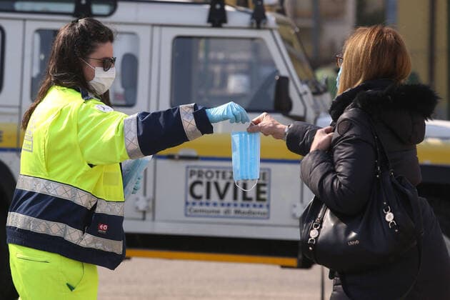 Coronavirus in Italien, Helfer verteilen Masken an einer Teststation in Modena
