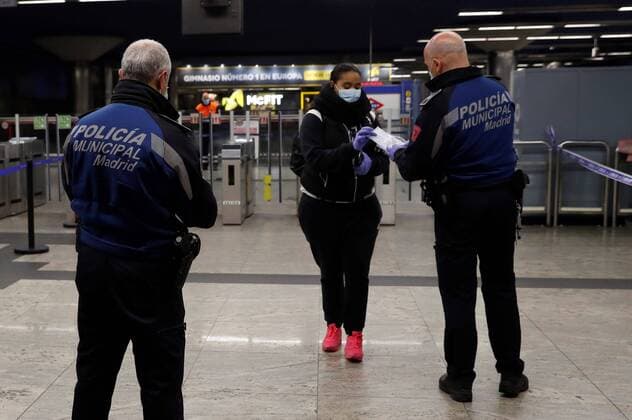 Coronavirus in Spanien, Polizei verteilt Schutzmasken an Pendler auf dem Weg zur Arbeit