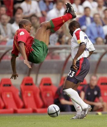 Jorge Andrade (Portugal, li.) fällt rücklings über Darius Vassell (England) Fußball EM Herren Euro 2004, Europameisterschaft, Länderspiel, Nationalmannschaft, Nationalteam, Viertelfinale, Vdig Gruppe Lissabon Dynamik, Höhe, Kampf,