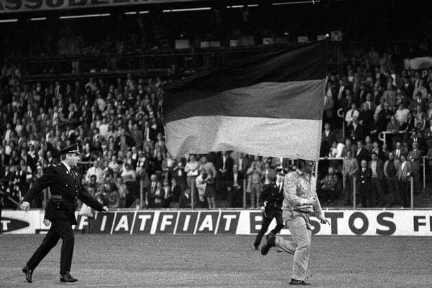 Ein deutscher Fan hat den Platz des Heyselstadions samt Nationalfahne gestürmt und wird von einem belgischen Polizisten verfolgt Fußball EM Herren Europameisterschaft 1972, Nationalmannschaft, Nationalteam, Nationaltrikot, Länderspiel, Finale Totale Nationalfahnen, verfolgen, rennen, flüchten, Brüssel, Verfolgungsjagd, Jagdszenen, Jagdszene