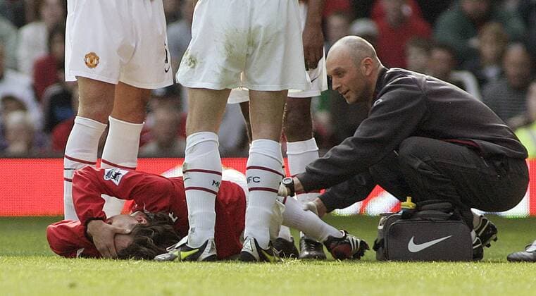 Gabriel Heinze (unten) krümmt sich vor Schmerz am Boden, Physiotherapeut Rob Swire (beide Manchester United) nimmt es augenscheinlich nicht ganz so ernst - EDITORIAL USE ONLY. No use with unauthorised audio, video, data, fixture lists, club league logos or live services. Online in-match use limited to 120 images, no video emulation. No use in betting, games or single club league player publications. Fußball Herren English Premier League 2004 2005, 1. Englische Liga, Manchester United, ManU Gruppe Manchester