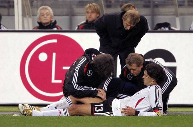 Michael Ballack muß sich von Mannschaftsarzt Dr. Hans Wilhelm Müller Wohlfahrt (li.) behandeln lassen, Bundestrainer Jürgen Klinsmann (hi.) und Physiotherapeut Klaus Eder (alle Deutschland) schauen interessiert zu Fußball Länderspiel Herren Länderspiel 2005, Freundschaftsspiel, Test, Testspiel, Nationalmannschaft, Nationalteam Gruppe medizinische Betreuung, Betreuer, Masseur Paris Teamarzt, Mediziner, Arzt, Doktor