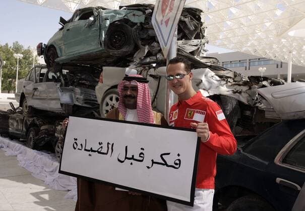 Michael Schumacher (Deutschland Ferrari, re.) mit einen Araber vor aufeinander gestapelten Autowracks Motorsport Grand Prix Herren Großer Preis von Bahrain 2006, Formel 1 Weltmeisterschaft, F1, F, GP, WM, Gruppe Sakhir, Schrift, Schriftzeichen, Manama