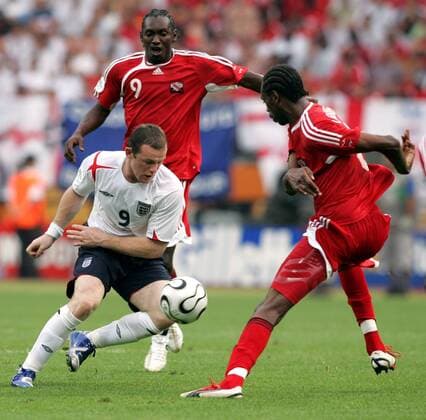Wayne Rooney (England, li.) gegen Dennis Lawrence (re.) und Aurtis Whitley (beide Trinidad und Tobago) - Fußball WM Herren WM 2006, Länderspiel, Nationalteam, Gruppe B, England - Trinidad und Tobago 2:0 Gruppe Nürnberg Dynamik, Fußball WM Herren WM 2006, Länderspiel, Nationalteam, Gruppe B, England - Trinidad und Tobago 2:0 Gruppe Nürnberg Dynamik,