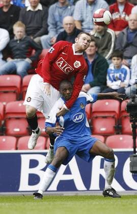 Wayne Rooney (Manchester United, li.) gegen Emmerson Boyce (Wigan) - EDITORIAL USE ONLY. No use with unauthorised audio, video, data, fixture lists, club league logos or live services. Online in-match use limited to 120 images, no video emulation. No use in betting, games or single club league player publications. Fußball Herren English Premier League 2006 2007, 1. Englische Liga, Wigan Athletic - Manchester United 1:3, ManU Gruppe Wigan Dynamik, Höhe, Kampf Fußball Herren English Premier League 2006 2007, 1. Englische Liga, Wigan Athletic - Manchester United 1:3, ManU Gruppe Wigan Dynamik, Höhe, Kampf